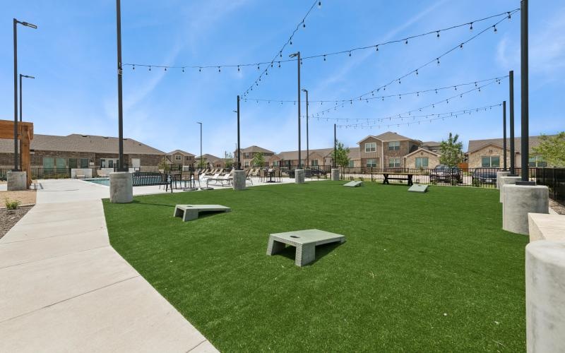 a grassy area with benches and a path with buildings in the background