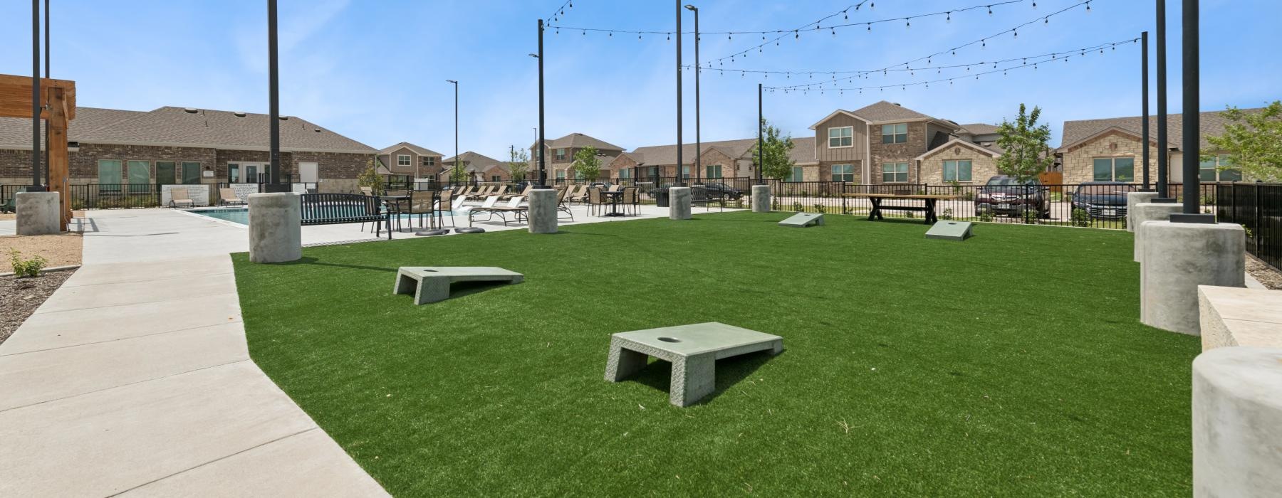 a grassy area with benches and a path with buildings in the background
